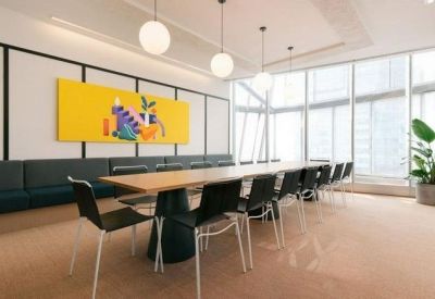 Bright conference room with a long wooden table, black chairs, and a vibrant yellow art piece.