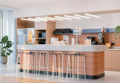 Modern office kitchen and bar area featuring tile accents and high stool seating.