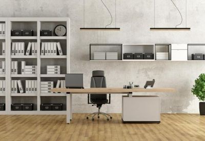 Minimalist private office with a light wood desk, ergonomic chair, and floor-to-ceiling bookshelf.