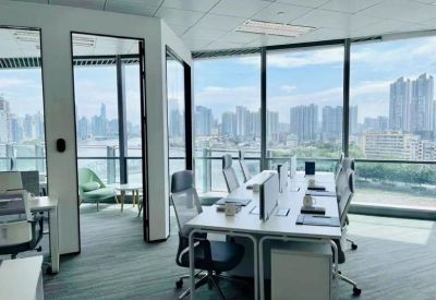 Bright open-plan workspace with white desks and panoramic floor-to-ceiling city views.