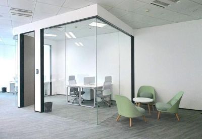 Glass-walled private meeting room with white furniture and a breakout seating area.