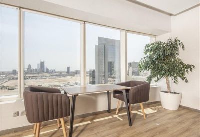 Breakout area with comfortable brown armchairs next to a large window and potted plant.