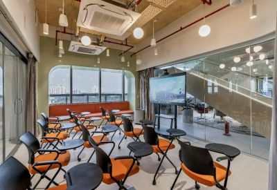 Classroom-style training room with orange chairs, individual tablets, and a large presentation screen.