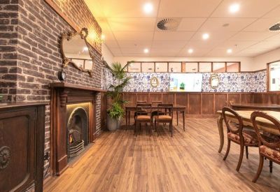 Traditional lounge or meeting room featuring a brick fireplace and ornate wooden furniture.