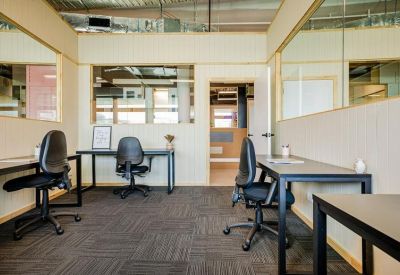 Small office space with desks and black chairs.