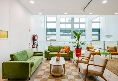 Bright lounge area with green sofas and large windows.