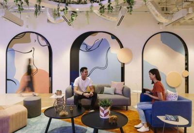Breakout area featuring colorful arched wall murals, plush sofas, and decorative hanging plants.