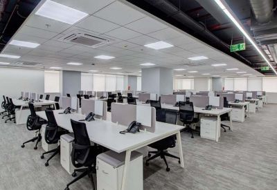 Bright open-plan office space with rows of white desks and ergonomic black chairs.