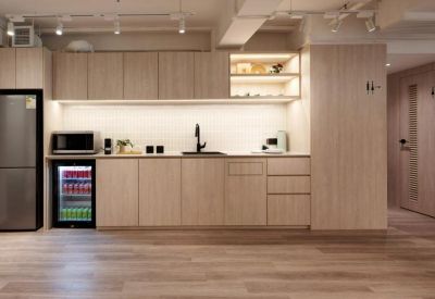 Modern communal kitchen with light wood cabinetry, integrated fridge, and a built-in beverage cooler.