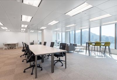 Bright coworking space with long wooden desks and views of lush green mountains.