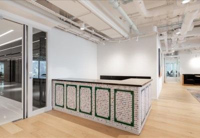 Modern reception desk with a patterned tile facade and warm wood flooring.