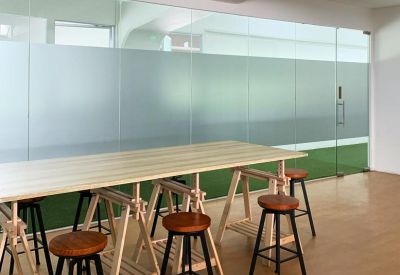 Open communal area with high wooden tables, bar stools, and a glass partition overlooking green space.