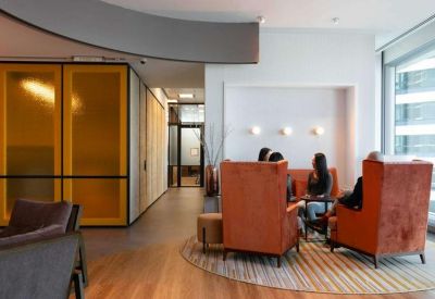 A warm lounge area with orange high-back armchairs and yellow partition walls.