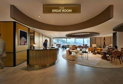 A sophisticated reception area with a curved wooden desk and The Great Room signage.