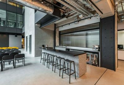 Modern communal cafe area with a grey stone breakfast bar and black bar stools.