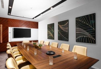 Professional boardroom with a long wood-grain table, cream leather chairs, and contemporary wall art.