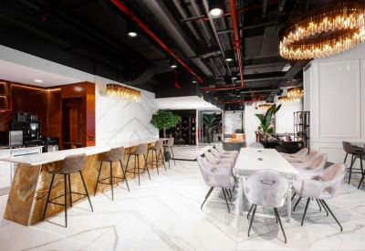 Bright breakout area with a marble cafe bar, high stools, and a long communal dining table.