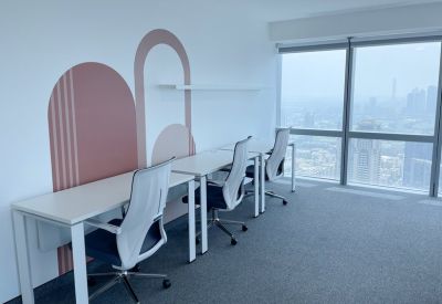 Bright coworking area with white desks and minimalist pink arch wall decals next to floor-to-ceiling windows.