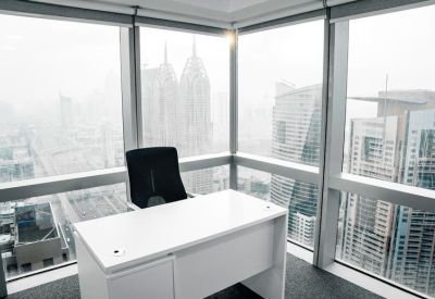 Sleek private corner office with a white desk and panoramic windows overlooking a dense cityscape.