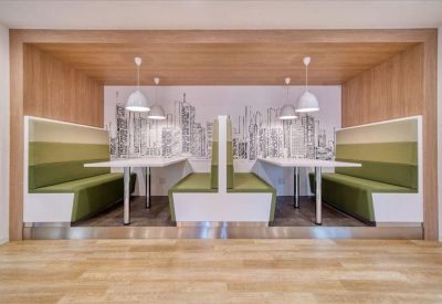 Modern breakout area with green cushioned booths and city-themed wall art in a wooden alcove.
