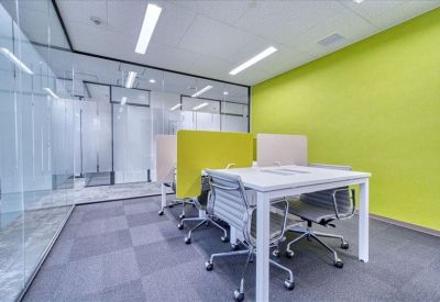 Professional workspace with four white desks divided by lime green and white privacy screens.