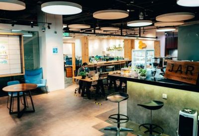 Cafe-style lounge with a coffee bar, round tables, and modern circular ceiling lights.