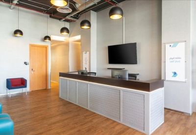 Reception area with a dark wood desk, industrial ceiling, and blue seating.