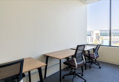 Bright workspace featuring two wooden desks by a large window.