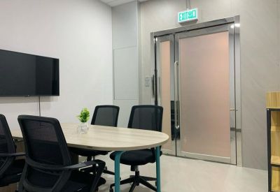 Meeting room with an oval table, black mesh chairs, and a wall-mounted television.