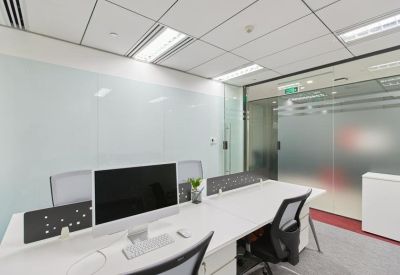 Shared workspace with white desks, ergonomic black chairs, and a glass partition.