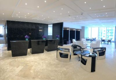 Modern reception lobby with dark marble desks and white designer armchairs.