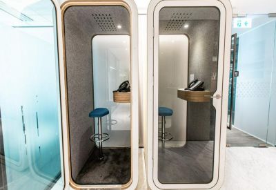 Private soundproof phone booths equipped with stools and task lighting for quiet calls.