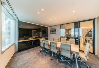 Contemporary meeting room with a long table, ergonomic mesh chairs, and glass partitions.