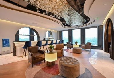 Modern lounge area with a sleek bar, leather armchairs, and city views.