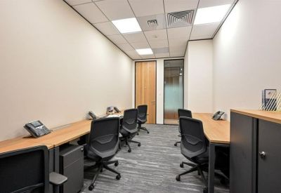Bright, narrow office with four workstations and sleek grey carpeting.