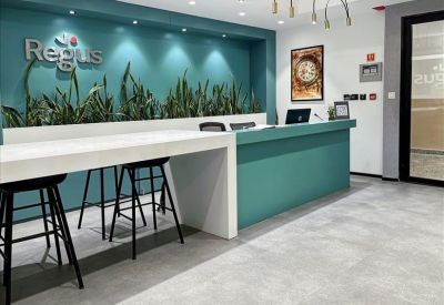 Bright reception area with a teal desk, white breakfast bar, and lush indoor plants.
