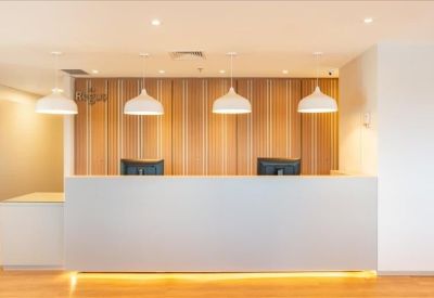 Modern reception desk with warm wood paneling and elegant white pendant lights.