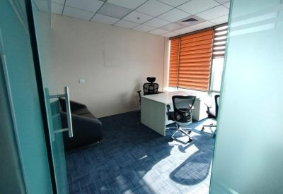 Private office suite with a white desk, ergonomic chair, and a black leather sofa.