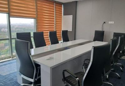 Bright conference room featuring a long white table and modern black ergonomic chairs.