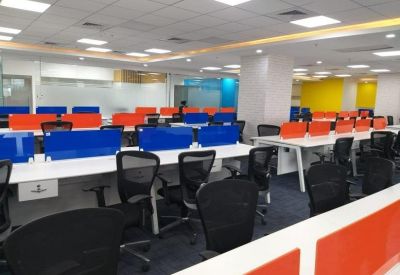Open-plan office space with rows of desks separated by blue and orange privacy screens.