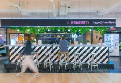 Coworking break area featuring a striped bar counter, stools, and hanging greenery.