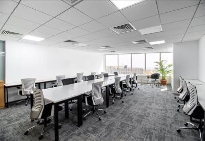 Spacious open-plan workspace with long white desks and ergonomic chairs.