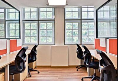 Quiet office room with rows of ergonomic black chairs and light wood desks.