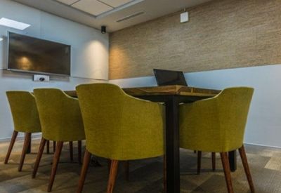 Modern meeting room with lime green chairs and a wooden conference table.