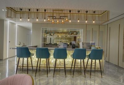 Modern bar counter with glowing front panel and five blue velvet bar stools.