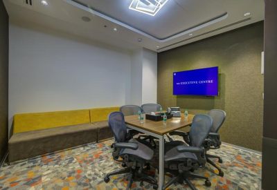 Small meeting room with a wooden table, ergonomic chairs, and a wall-mounted TV screen.