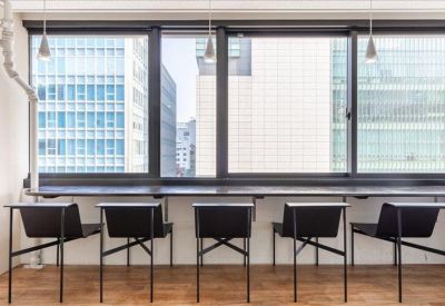 Compact two-person office with light wood desks and black ergonomic chairs.