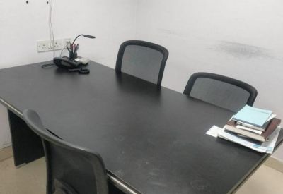 A black rectangular meeting table with three mesh office chairs.