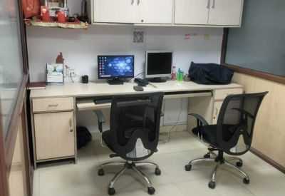 Twin workstation setup with monitors, ergonomic chairs, and a small wall shrine.