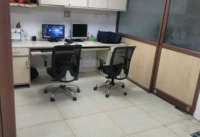 Workstation area with multiple computers, office chairs, and overhead storage cabinets.